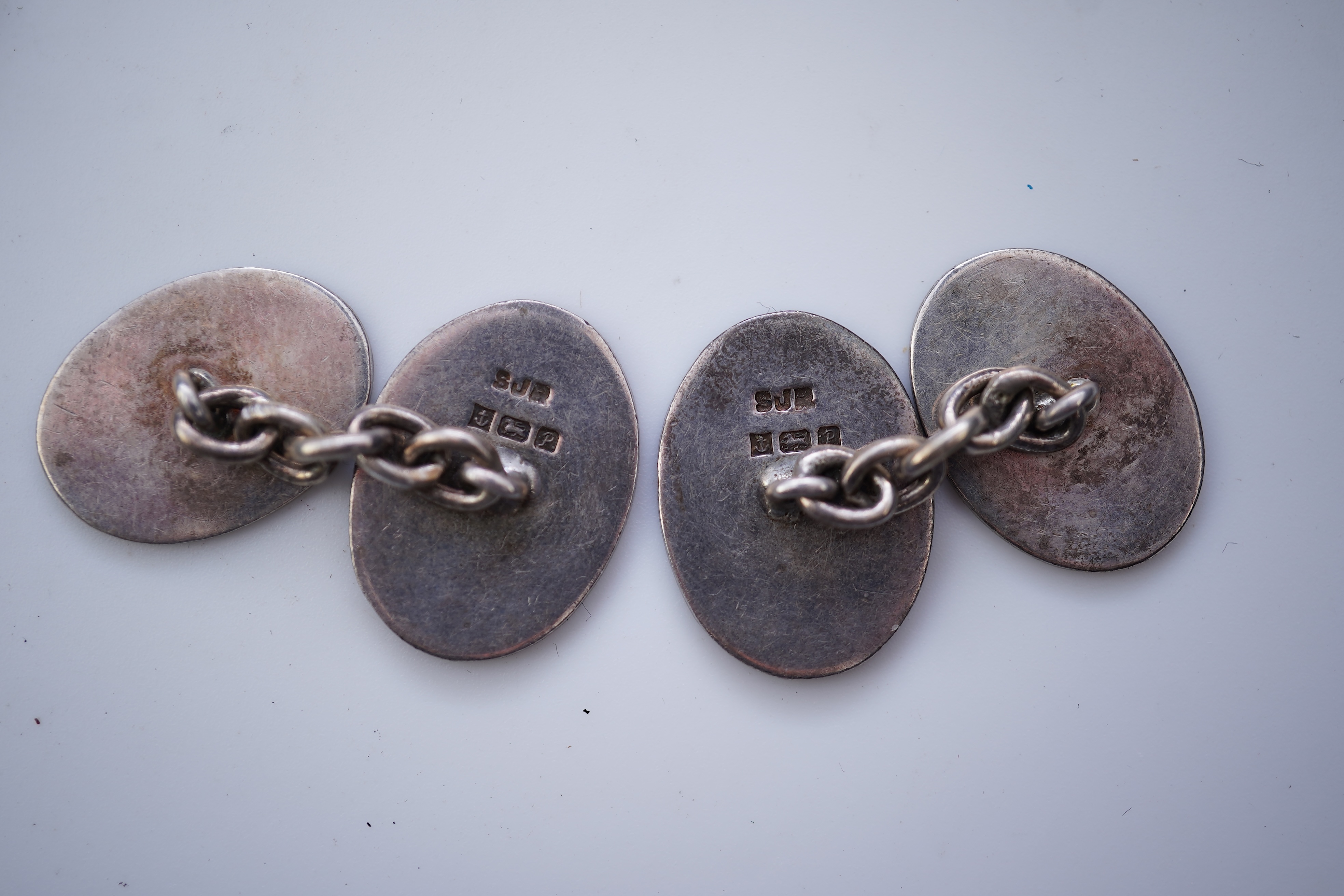 A collection of silver jewels, comprising: a bangle; a chain necklace suspending two winding toothpicks, one with toothpick deficient; a rope twist chain; a pair of cufflinks with the initials DBH; a pendant of abstract